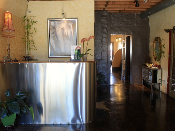 Modern salon reception area with sleek metal counter and cozy decor, promoting professional beauty services.